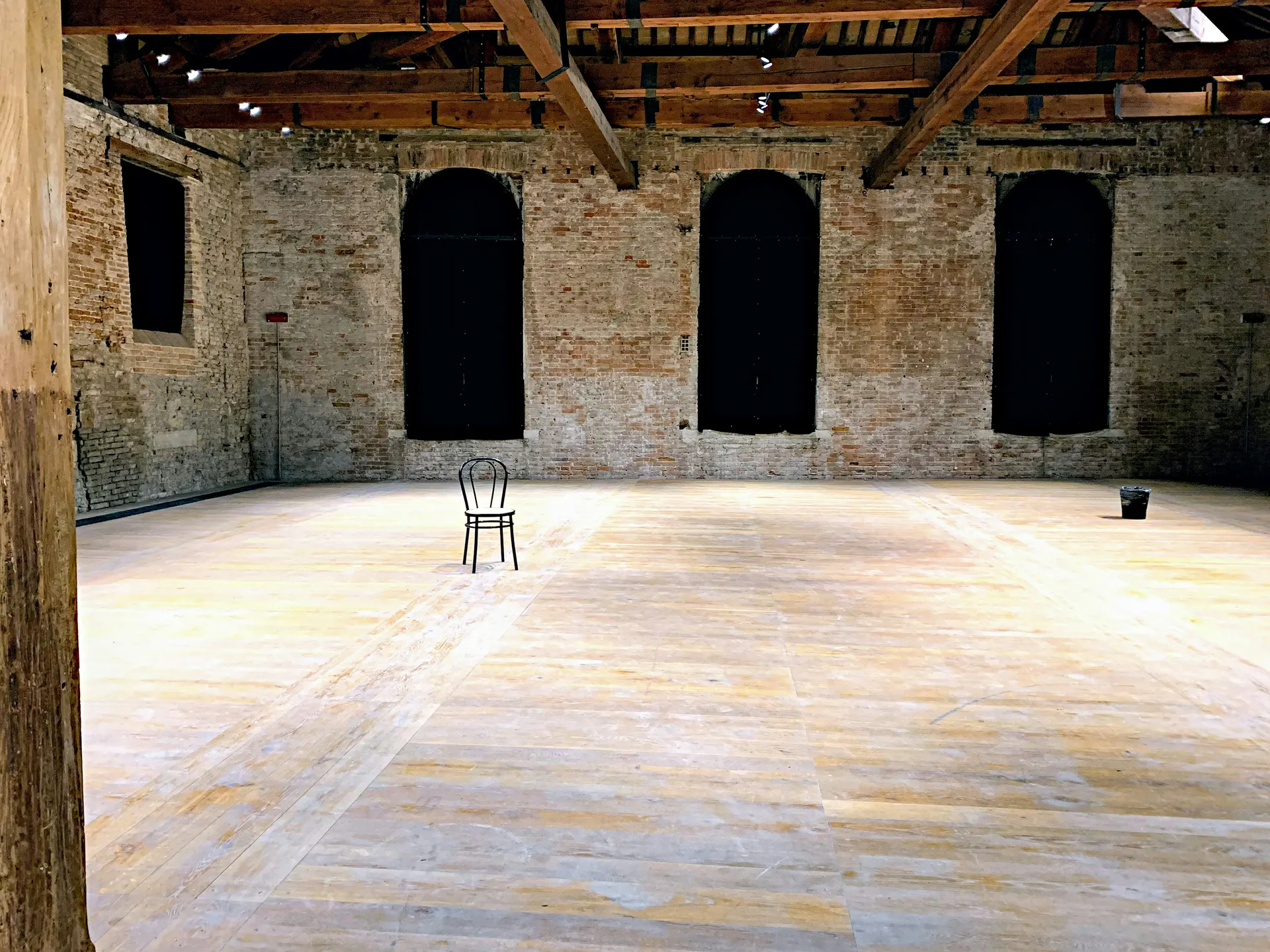 Open dance studio with wood floor, brick walls, and natural light